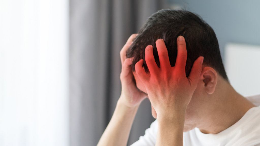 Man holding his head in pain - Concussion Treatment and Recovery Services offered in Toronto, Oakville, Hamilton and Virtually is available with The Therapy Centre