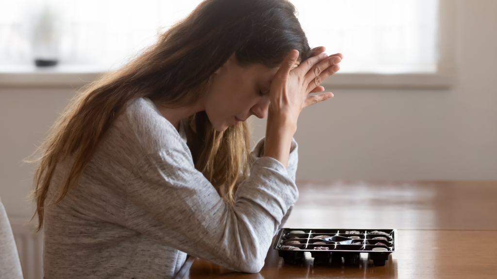 Upset Woman leaning over box of chocolates - Eating Disorder Program is available at The Therapy Centre with locations in Toronto, Oakville and Hamilton (GTA)