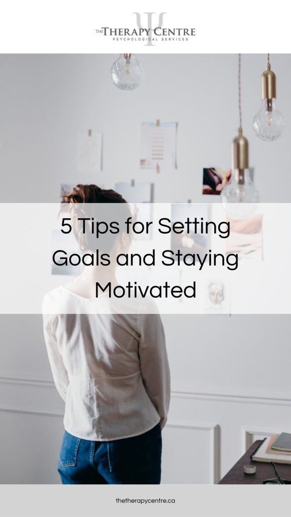 Woman looking at images pinned to wall - 5 Tips for Setting Goals and Staying Motivated - Article by The Therapy Centre