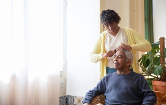 A daughter combing her father's hair - The Stress of Being a Caregiver: Finding Support for Your Mental Health - Article by The Therapy Centre