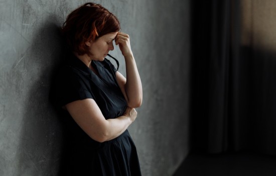 Tired woman leaning against a wall - - The Stress of Being a Caregiver: Finding Support for Your Mental Health - Article by The Therapy Centre